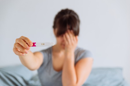sad woman shows negative pregnancy testの写真素材
