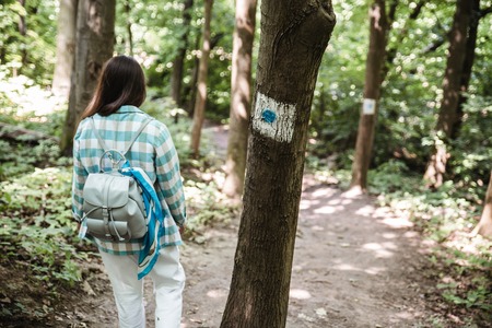 woman walking by wooden park view from behindの写真素材