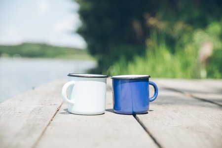 two metal cups with tea. river on background. summer time conceptの写真素材