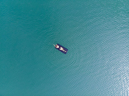 woman on mattress in azure water. overhead view. copy space. summer time