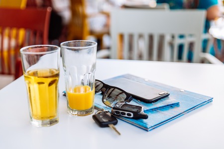 two glass of cool drinks on cafe table with phone menu and car keys
