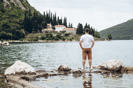 man standing at cliff with beautiful view of sea and mountains. summer time conceptの写真素材