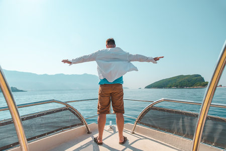 man standing with rising hand at nose of the boat. summer vacationの写真素材