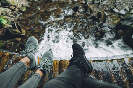 legs of two persons with waterfall on background. copy space