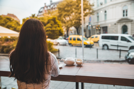 woman sitting in cafe with big glass window and beautiful view of autumn city street. lifestyleの写真素材