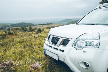 suv car at the top of the hill in autumn rainy weather. copy spaceの写真素材