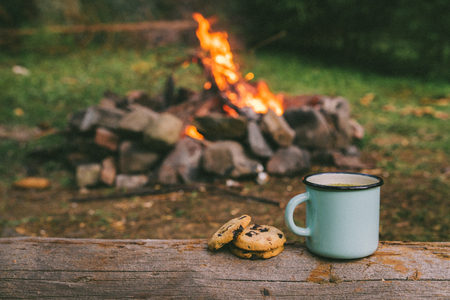 metal cup with tea and cookies. fire on background. union with natureの写真素材
