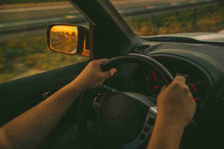 man driving car by highway on sunset. road tripの写真素材