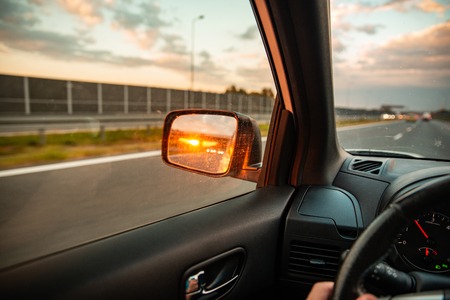 first-person point of view. sunset in car mirror. road trip