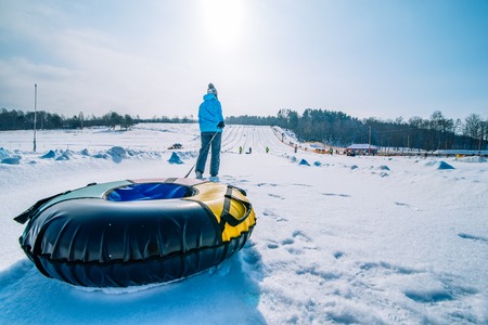young girl pull sleigh. snow tubing. sunny snowed dayの写真素材