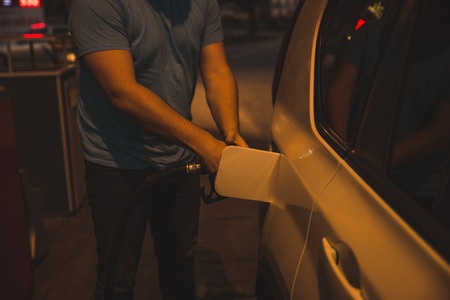 man fueling up the car in the evening on gas stationの写真素材
