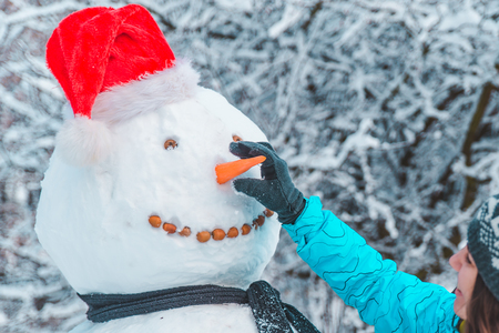 hand put carrot nose to snowman close up conceptの写真素材