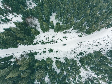 overhead view of suv car in snowed winter forest. travel concept