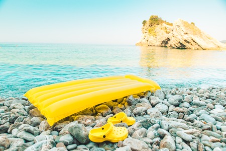 inflatable yellow mattress shoes for rocks at sea beach. summer vacation conceptの写真素材