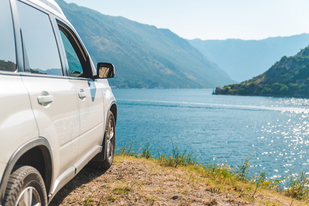 white suv car parked at seaside with beautiful view of bay with mountains. road tripの写真素材