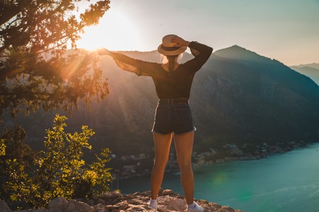 woman standing on the top of hill. kotor with sunset on background. summer travel conceptの写真素材