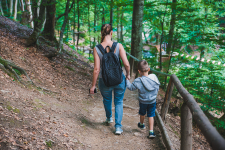 mother with son walking forest trail holding hands. travel conceptの写真素材