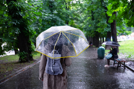 rainy weather. woman walking with umbrella by city park.の写真素材