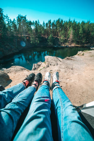 couple sitting in car trunk lake on background. legs in sneakers and jeans. travel conceptの写真素材