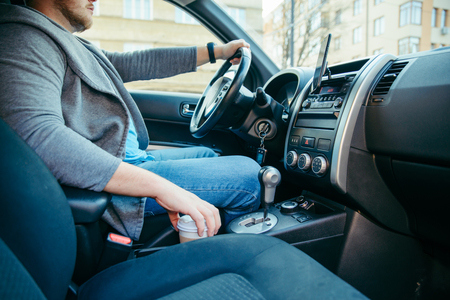 young man driving car. coffee cup in cup holder. lifestyleの写真素材