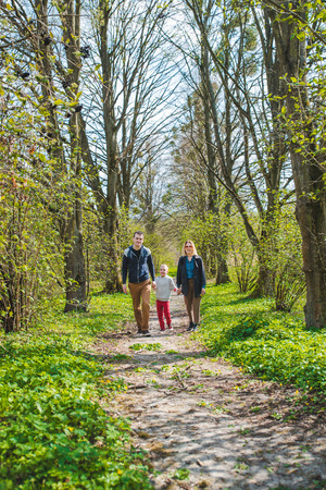 family of three walking by park trail in sunny day. happy kidの写真素材