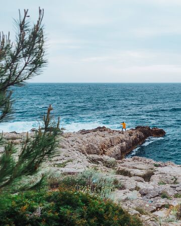 man walking by rock to storming sea. copy spaceの写真素材