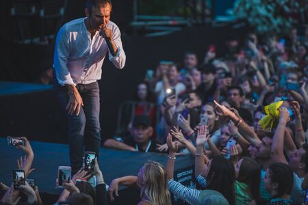 LVIV, UKRAINE - June 18, 2019: rock band singer on stage with microphone crowd around stage shooting...