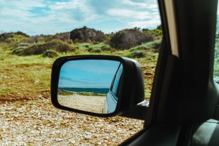 sea reflection in car rear mirror. road trip. summer vacation