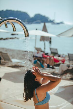 woman taking shower at sea beach. wash out salt water. summer vacationの写真素材