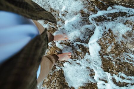 overhead view man barefoot walking by sea rocky beach. copy spaceの写真素材