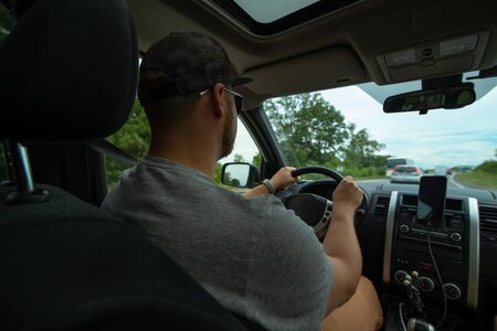car travel concept view from inside young caucasian man driving car by speedway