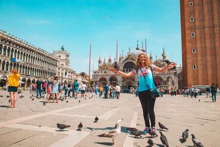 Italy, Venice - May 25, 2019: tourist woman at saint marks square with doves summer vacationのeditorial素材