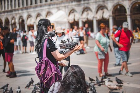 Italy, Venice - May 25, 2019: tourist woman at saint marks square with doves summer vacationのeditorial素材