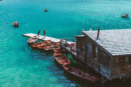 BRAIES, ITALY - June 13, 2019: view of wooden house on water with pier and boats lake in dolomites mountains. hiking placeのeditorial素材
