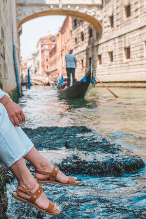 woman sitting at city quay at venice italy enjoying the view of canals with gondolasの写真素材