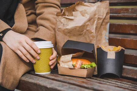 woman hands close up holding burger with coffee cup. fast food conceptの写真素材