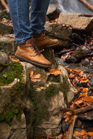 men legs at rocks near stream autumn weather hiking