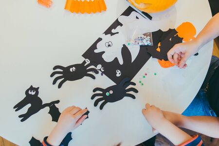 young mother with toddler son making craft spiders for halloween holiday family timeの写真素材