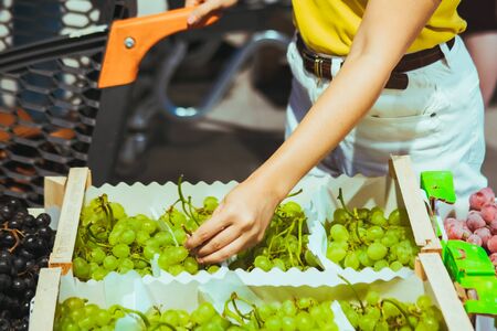 woman hand taking grapes from the box at store market grocery shopping concept