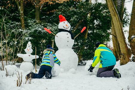 little cute boy making snowman. rolling big snowball. winter leisureの写真素材