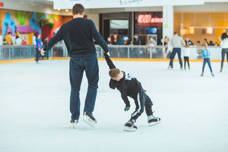 LVIV, UKRAINE - February 3, 2019: father teaching son how to skate on ski rink. family timeのeditorial素材