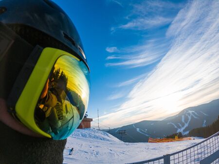 man in ski mask close up. reflection. snowed mountains on sunset. copy spaceの写真素材