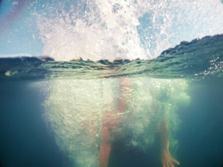 man jumping in blue clear water summer time