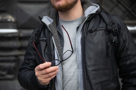 man in leather coat holding eyeglasses copy spaceの写真素材