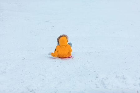 woman sliding from the snow hill in yellow coatの写真素材
