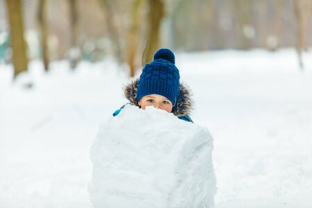 little cute boy making snowman. rolling big snowballの写真素材