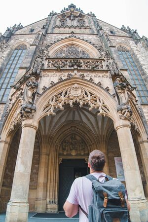 tourist man with backpack looking at old gothic church copy spaceの写真素材