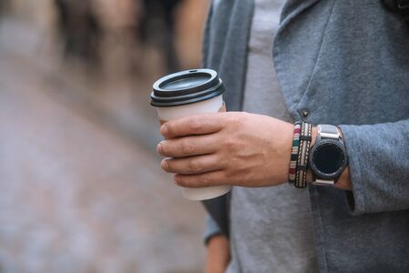 man hand close up holding disposable coffee cup smart watch with bracelet on wristの写真素材