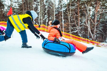 LVIV, UKRAINE - January 7, 2019: young woman preparing to slide down by hill on snow tube. winter leisureのeditorial素材