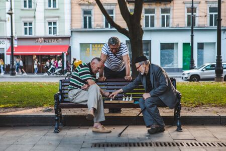 Lviv, Ukraine - August 3, 2019 - seniors playing chess at city bench park. summer timeのeditorial素材